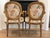 An elegant pair of vintage Louis XVI style carved wood fauteuil armchairs in floral chinoiserie upholstery. The chairs are...