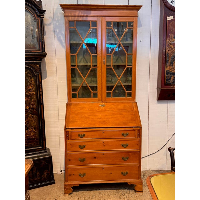 Astragal glazed doors above open to shelves painted a soft green, and the fall front below drops to a fitted interior of...