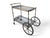 Brass bar cart with double glass shelves, elegant and functional. Equipped with a top handle, rear spoked wheels, and...