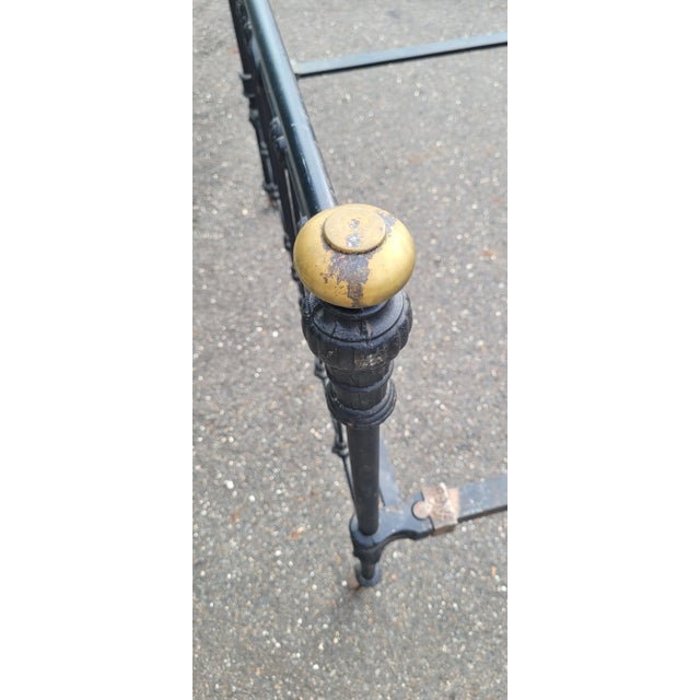 Antique iron bed frame dating to the late 19th century / early 20th. Featuring black painted iron frame, brass caps, on...