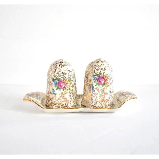 A vintage, mid-century, English bone china set of salt shaker, pepper shaker, and holding tray, with gold gilt chintz...