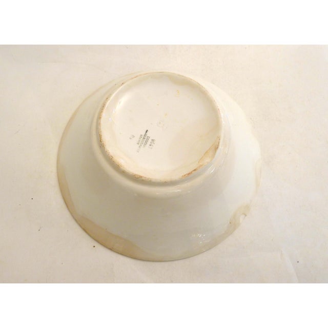 Round, flared salad bowl with a wide, flat rim, decorated with a stylized floral design applied using a stencil. White...