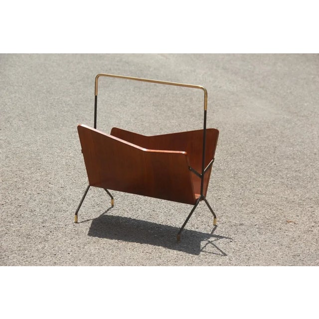 This Italian magazine rack features a black metal structure, brass parts, and geometric rosewood holders.