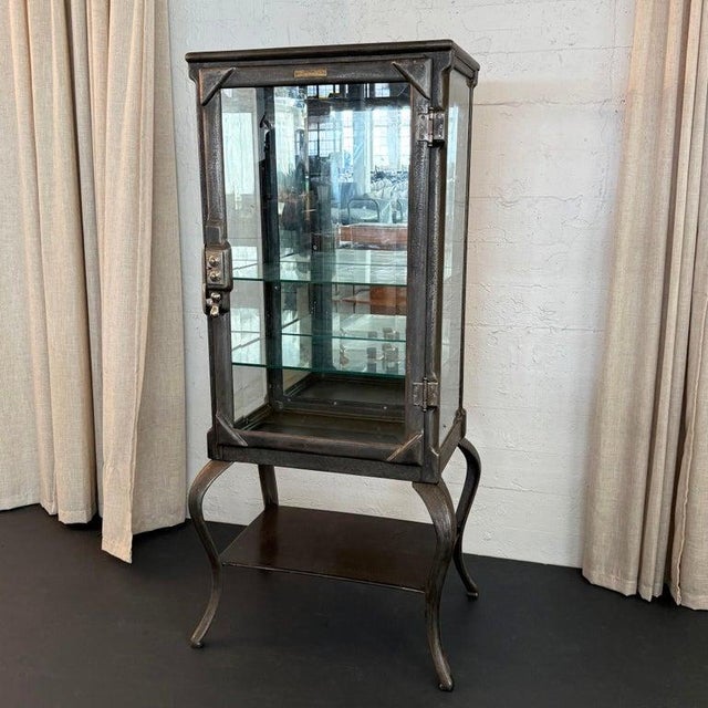 This antique, industrial, brushed steel apothecary vitrine cabinet was manufactured by Clark & Roberts of Indianapolis,...