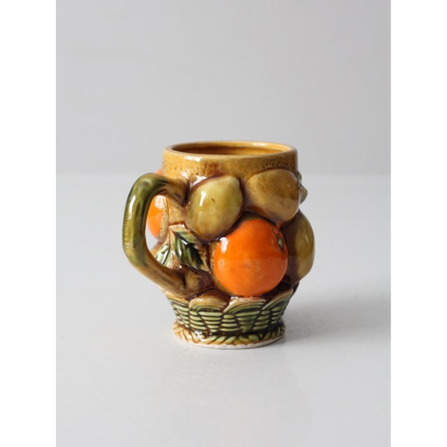 A vintage Inarco fruit mug featuring a richly detailed basket design layered with dimensional citrus and leaves. The...