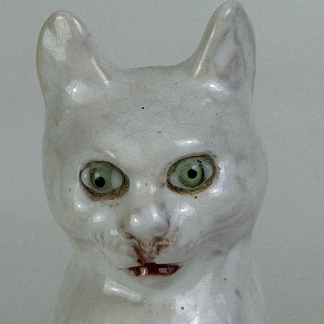 A rare to market pair of vintage French white tin glazed terracotta figurines of green glass eyed cats. One is stamped...