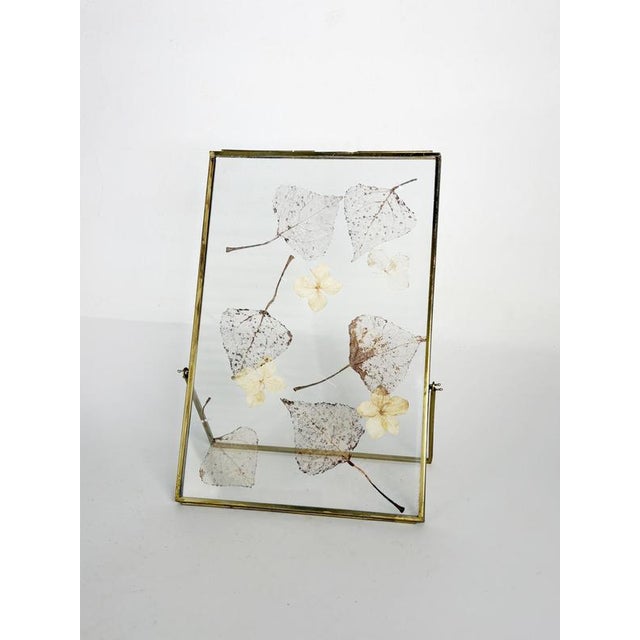 Decorative French tabletop picture frame featuring genuine pressed leaves and delicate dried flowers elegantly suspended...