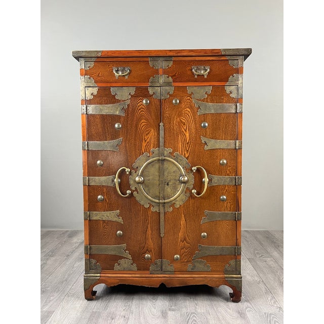 Superb Japanese tansu-style cabinet in wood with a beautiful patina, richly adorned with decorative brass fittings. The...