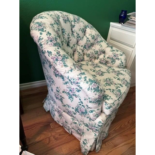 The chair is a classic upholstered club chair featuring a distinct floral print on a dot-patterned background. It is...