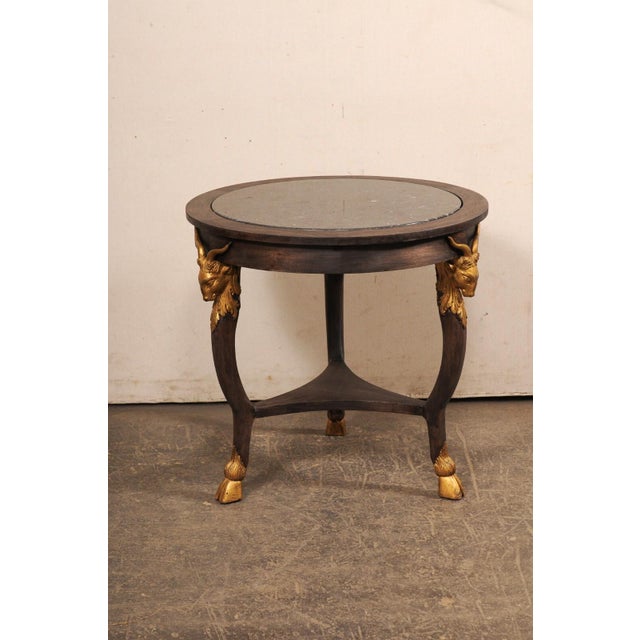 A French vintage round occasional table with marble top and goat head accents. This smaller-sized table from France...