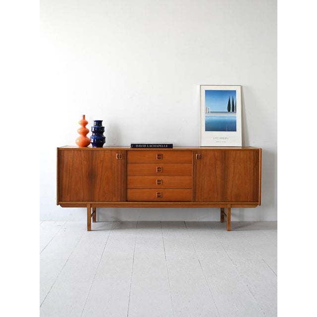 Original 1960s sideboard with drawers and sliding doors. The sculpted wooden grips add a refined detail to the essential...