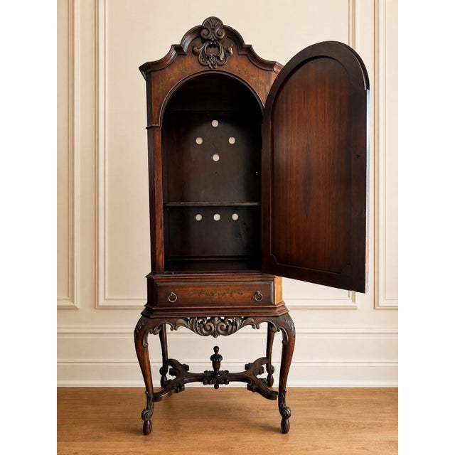 A highly decorative early 20th century Continental cabinet on stand, richly detailed with an arched paneled door, carved...