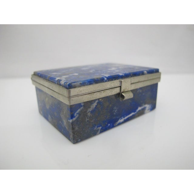 Wonderful little decorative trinket box featuring a polished lapis lazuli stone framed with silver metal. Hinged lid opens...