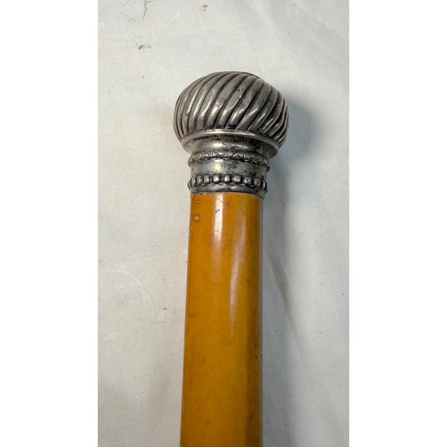 This antique sterling silver and malacca wooden walking stick is a unique piece that exudes craftsmanship and elegance....