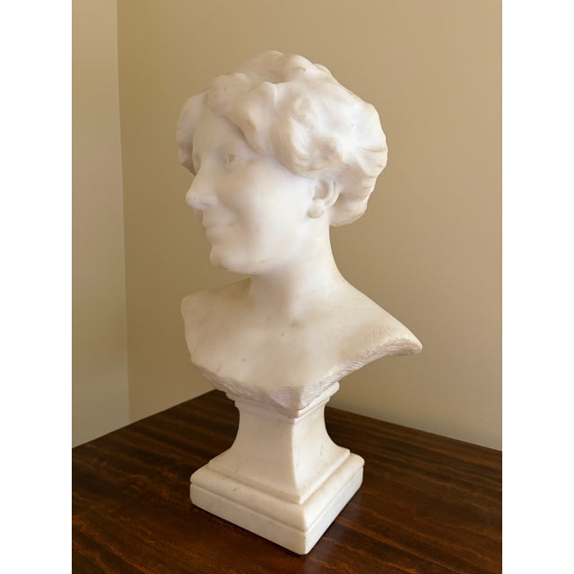 A beautifully carved Carrara marble bust of a young woman, created in France during the 1920s and signed by sculptor Paul...