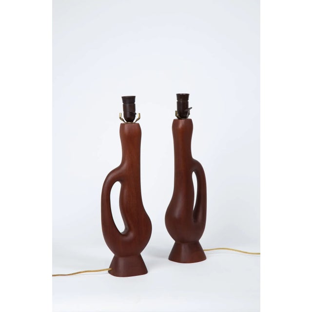 Pair of handcrafted organic form teak lamps with original woven lampshades. Bakelite sockets and light switches. Overall...