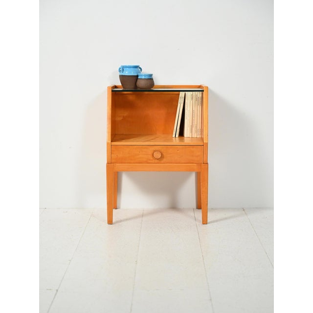Scandinavian birch burl bedside table from the 1940s and 1950s, trapezoidal profile, drawer, glass shelf, and carved...