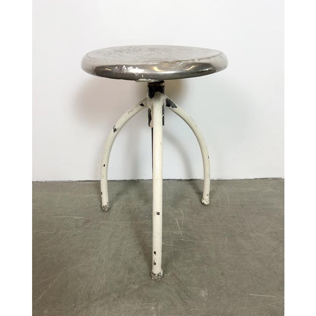 Industrial three-legged medical stool made in former Czechoslovakia during the 1960s. It features a white legs and a...