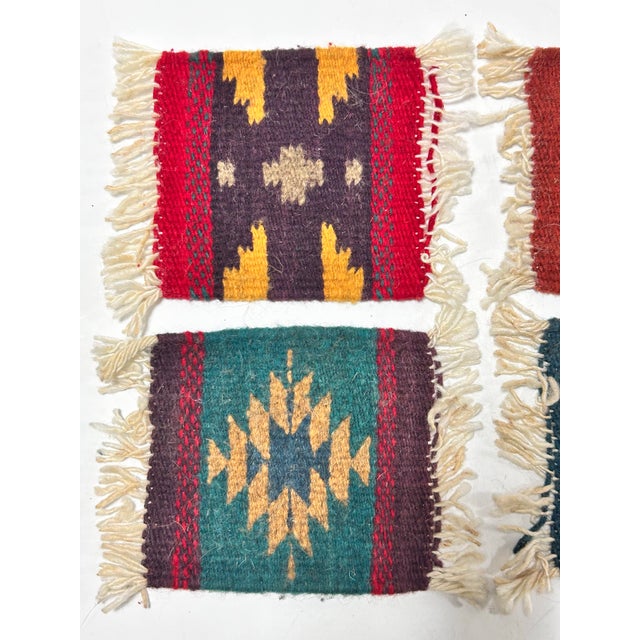 A colorful set of four vintage woven wool coasters featuring bold Southwestern geometric motifs in red, turquoise, gold,...