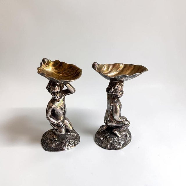 A charming pair of figural table salts, stamped Elkington Plate, likely Edwardian and in a late Victorian taste. Each...