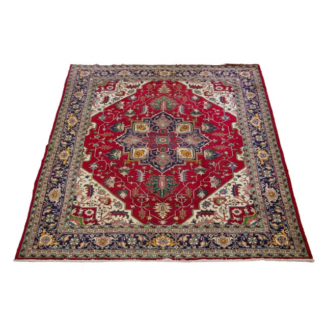 This Vintage Heriz wool rug has a red field with multicolor accents all over the design. This rug measures 9'7" x 12'3".