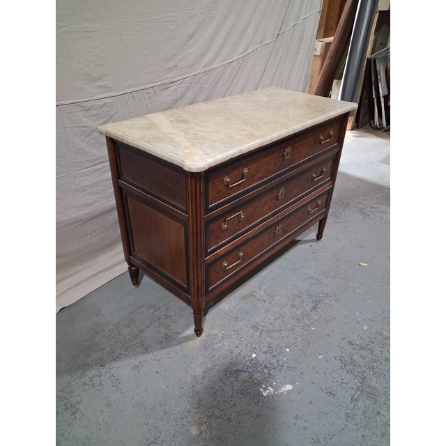 An elegant late 18th-century French Louis XVI commode, richly figured walnut and topped with its original white marble...