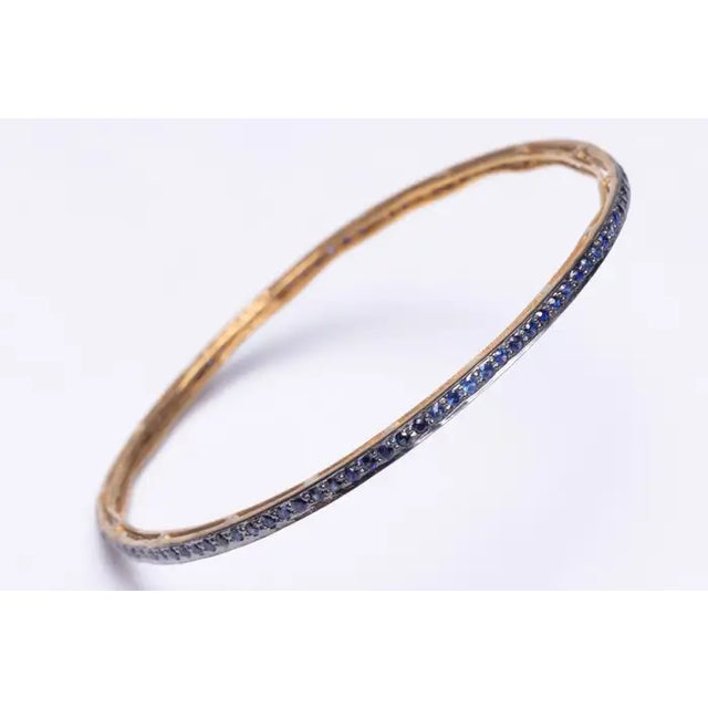 A pair of faceted, round sapphire bangles in an 18K gold setting. Inside circumference measures 2.5" Easy to stack with...