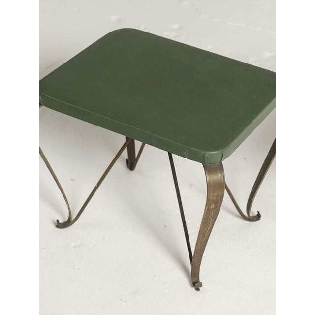 A charming pair of Mid-Century Modern Italian stools, featuring green faux leather upholstery and elegantly sculpted brass...
