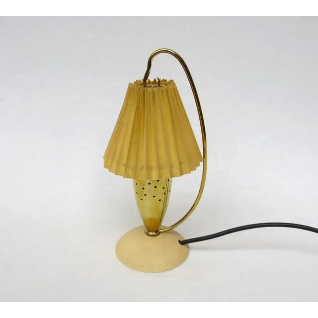 An extraordinary, petite table lamp from the 1950s. The lampshade acts like a lantern. The lampshade is made of linen...