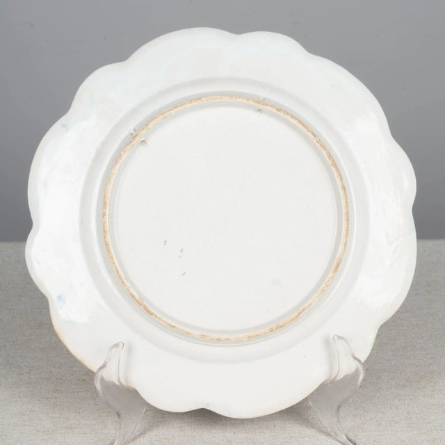 A Henriot Quimper French faience hand painted decorative plate, depicting a woman with water jug. Wide scalloped rim with...