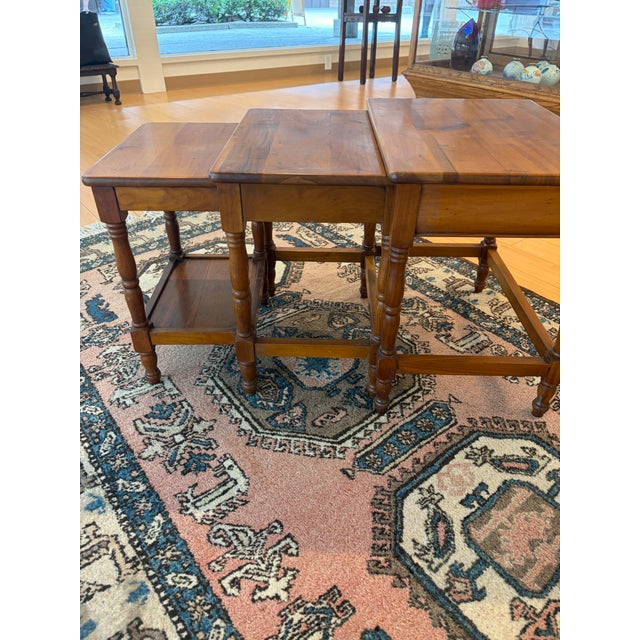 Charming set of three vintage nesting tables crafted in warm-toned. The smallest table includes a lower shelf for...