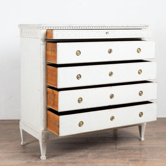 Early 19th century tall Danish chest of five drawers, crafted in pine. The narrow upper drawer features a carved Greek key...