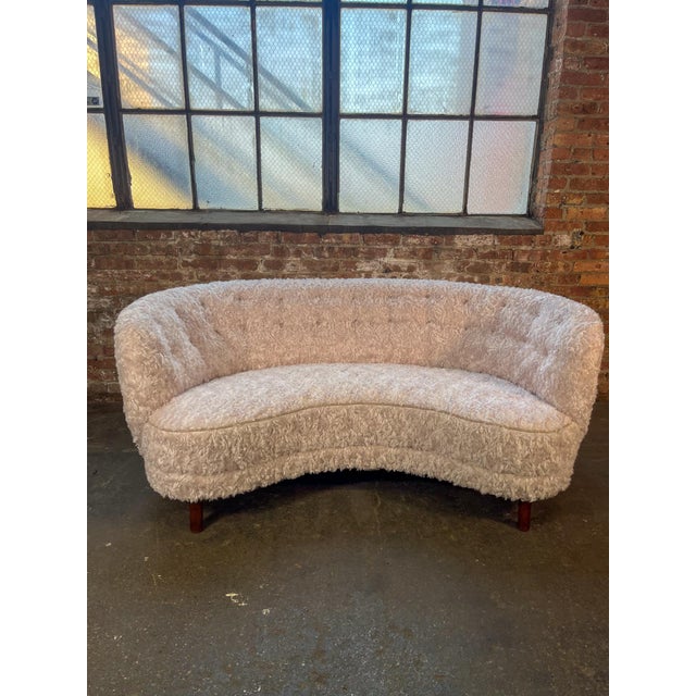 Beautiful Swedish curved sofa in newly upholstered curly ivory fabric. The rounded back and gently curved seat create an...