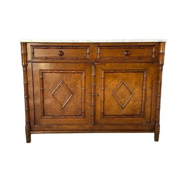 Birdseye Maple Faux Bamboo Cabinet with White Marble Top. Cabinet features a faux bamboo carved frame. It is fitted with...