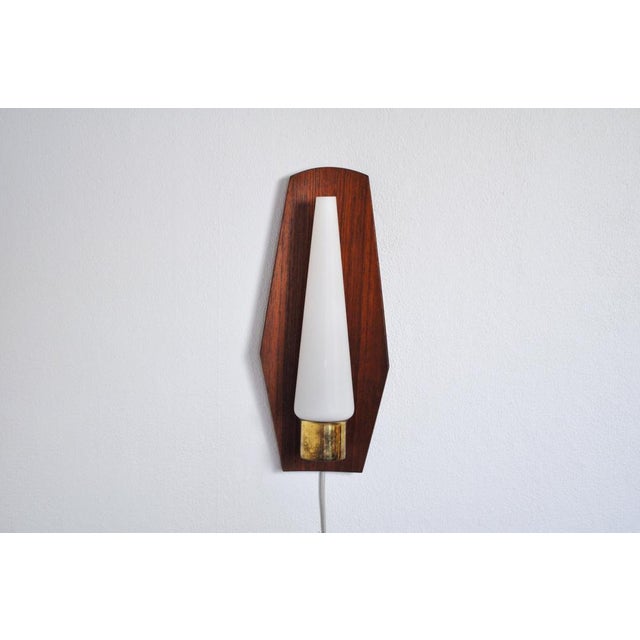 Mid-Century Modern wall light in a slightly bowed teak, brass and opaline glass shade. Probably made in Denmark the 1960s....