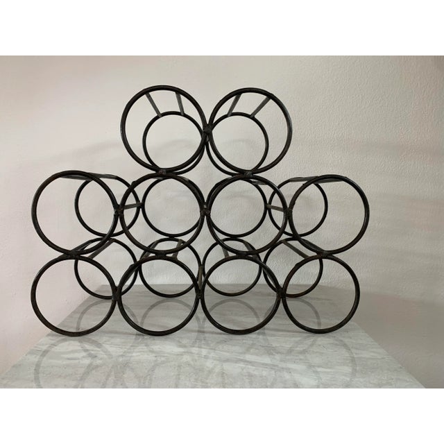 A vintage mid-century modernist welded iron wine rack featuring a minimalist 10-bottle stacked design.