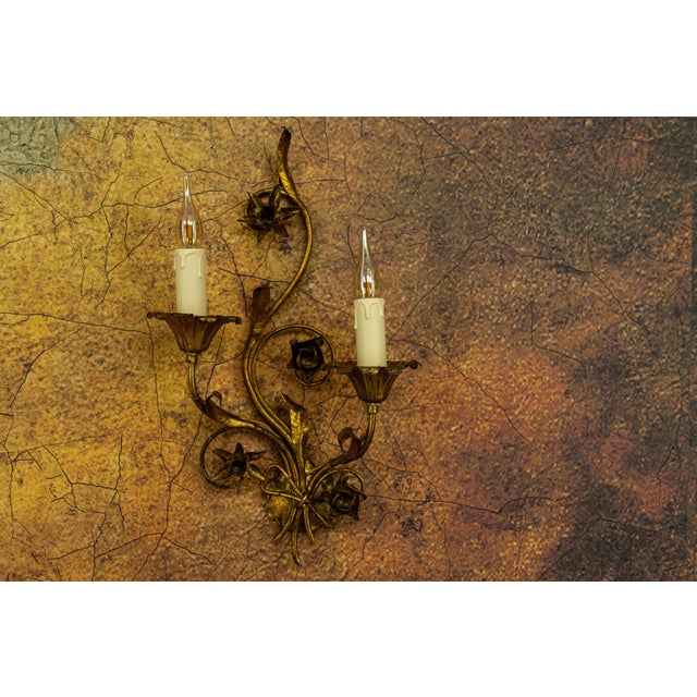 Hollywood Regency gilt metal wall sconce, circa 1950s. Elegant two-light wall sconce crafted in gilt metal, featuring...