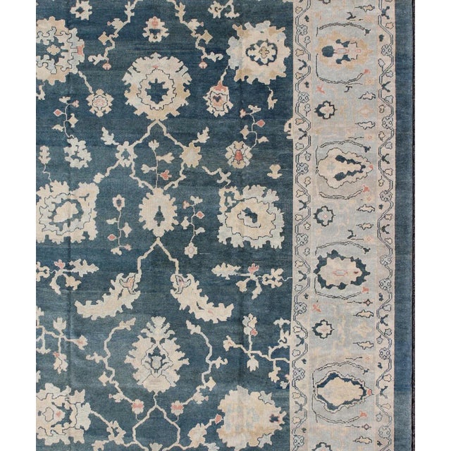 Turkish large Oushak rug with large flower design in teal blue, ice blue/ gray and accent colors of coral and butter....
