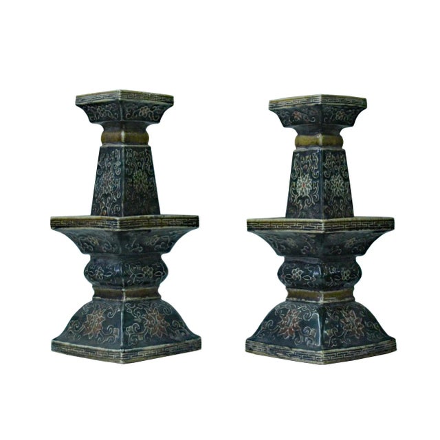 This is a pair of handmade ceramic distressed black color finish square shape candle holders display with dimensional...