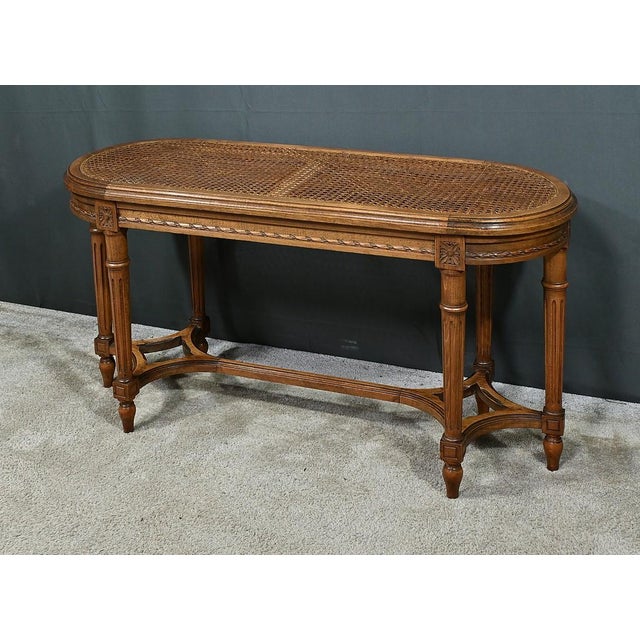 This walnut piano bench, in the refined Louis XVI style, embodies the timeless elegance of period furniture. Its oblong...