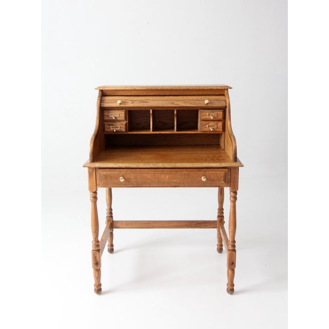 Vintage oak roll top secretary desk showcasing timeless craftsmanship and classic design. A gracefully curved tambour...