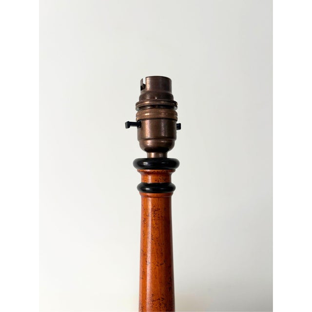 A simple 20th century column table lamp, with a circular stem and base featuring ebonised banded details in a neoclassical...