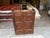 The Reclaimed Teak Cabinet with 2 drawers is a solid rectangular cabinet made of teak wood with an aged metal handle...
