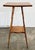 Handmade antique two tier side table with four petite turned splay wood legs attached by lower stretcher shelf. Square top...