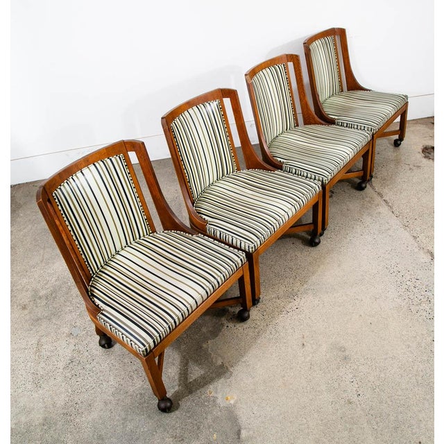 Rolling American designed dining chairs, unknown designer. Walnut construction throughout the chair. Vinyl upholstery with...