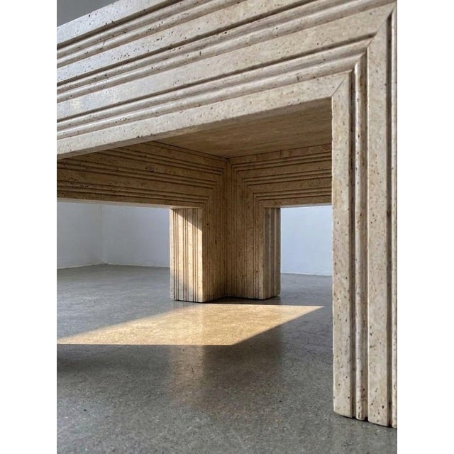 Solid coffee table made from natural travertine stone with a bold architectural design. The table features a clean square...
