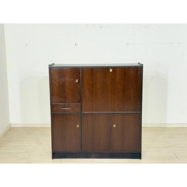 Beautiful vintage writing desk from the 1960s in an elegant mahogany finish. This classic secretary desk is a true storage...
