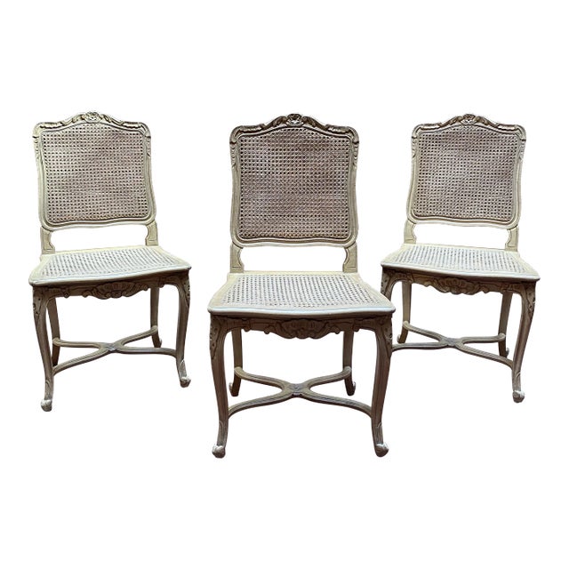 Provincial Louis XV style carved wood and caned dining chairs. Each chair features cane back and seat, carved stretcher,...