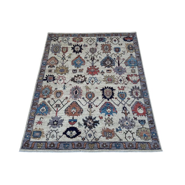 An allover Oushak-design carpet on a soft ivory ground, scattered with folk animals and figures. Large angular palmettes,...