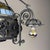 Italian vintage wrought iron chandelier featuring floral metalwork, decorative scrolls, and a colorful stained glass...